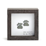 A shadow box with a wooden frame, featuring a silhouette of a pet's paw print on a heart-shaped background, with the text 'Paw Prints on My Heart'. Available at Be Charmed