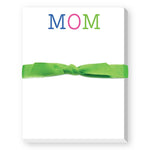 A mini notepad with 'MOM' written on the cover in colorful letters, tied with a green ribbon. Available at Be Charmed