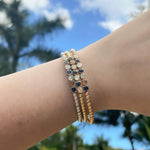 Stack of beaded bracelets on a wrist with a blurred natural background. Available at Be Charmed