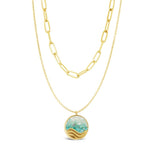 Gold layered necklace with a turquoise pendant on a white background. Available at Be Charmed