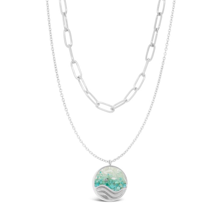 Layered Silver Necklace with a round pendant featuring a wave design on a white background. Available at Be Charmed