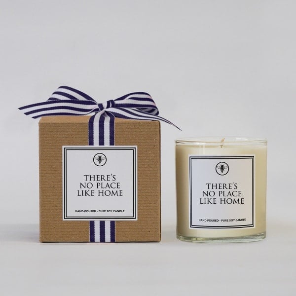 Ella B. 11 oz Candle – There’s No Place Like Home. A cozy, hand-poured soy candle perfect for gifting or warming up any space. Available at Be Charmed.