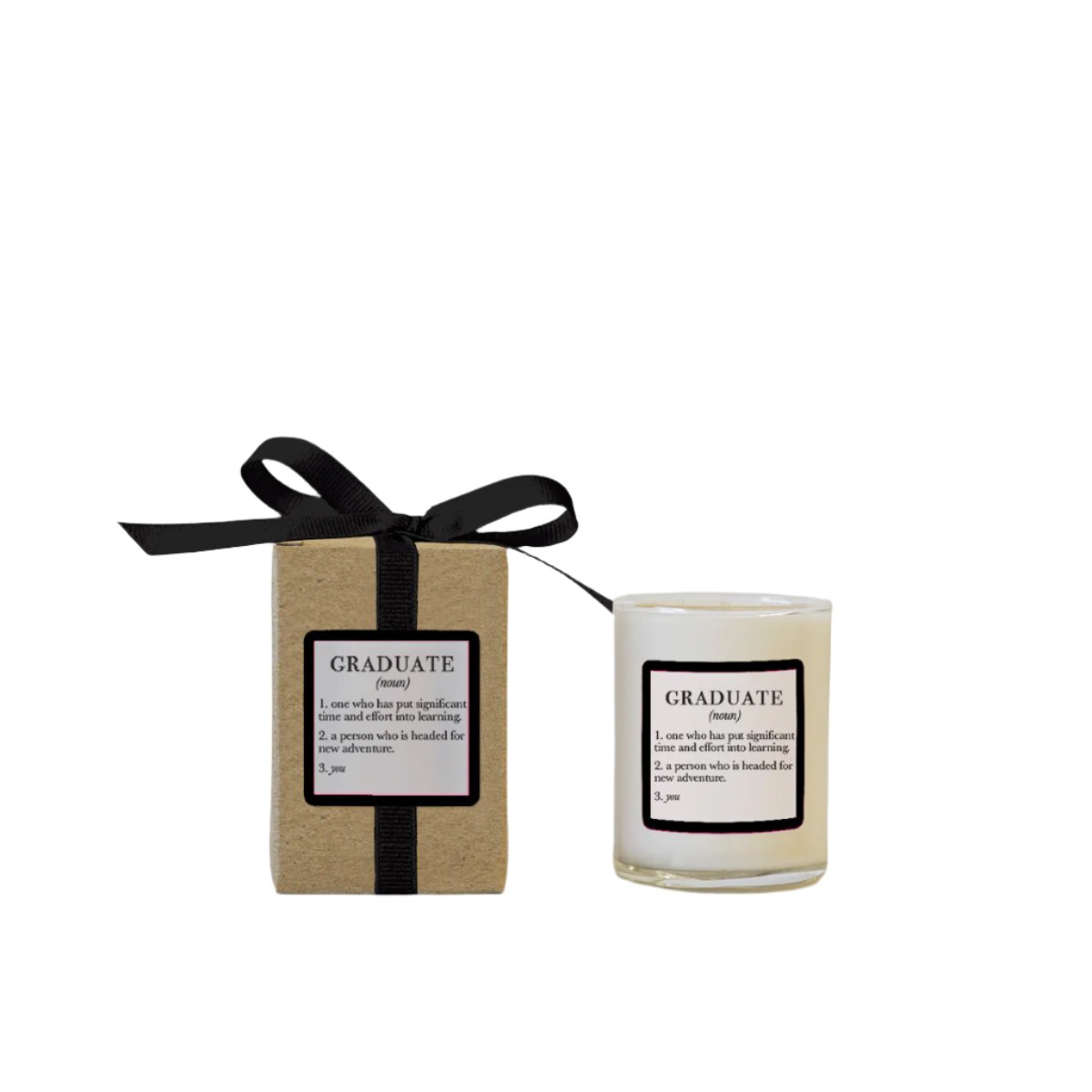 A 3 oz. soy candle with the label 'GRADUATE' on a black and brown cardboard packaging, tied with a black ribbon. Available at Be Charmed