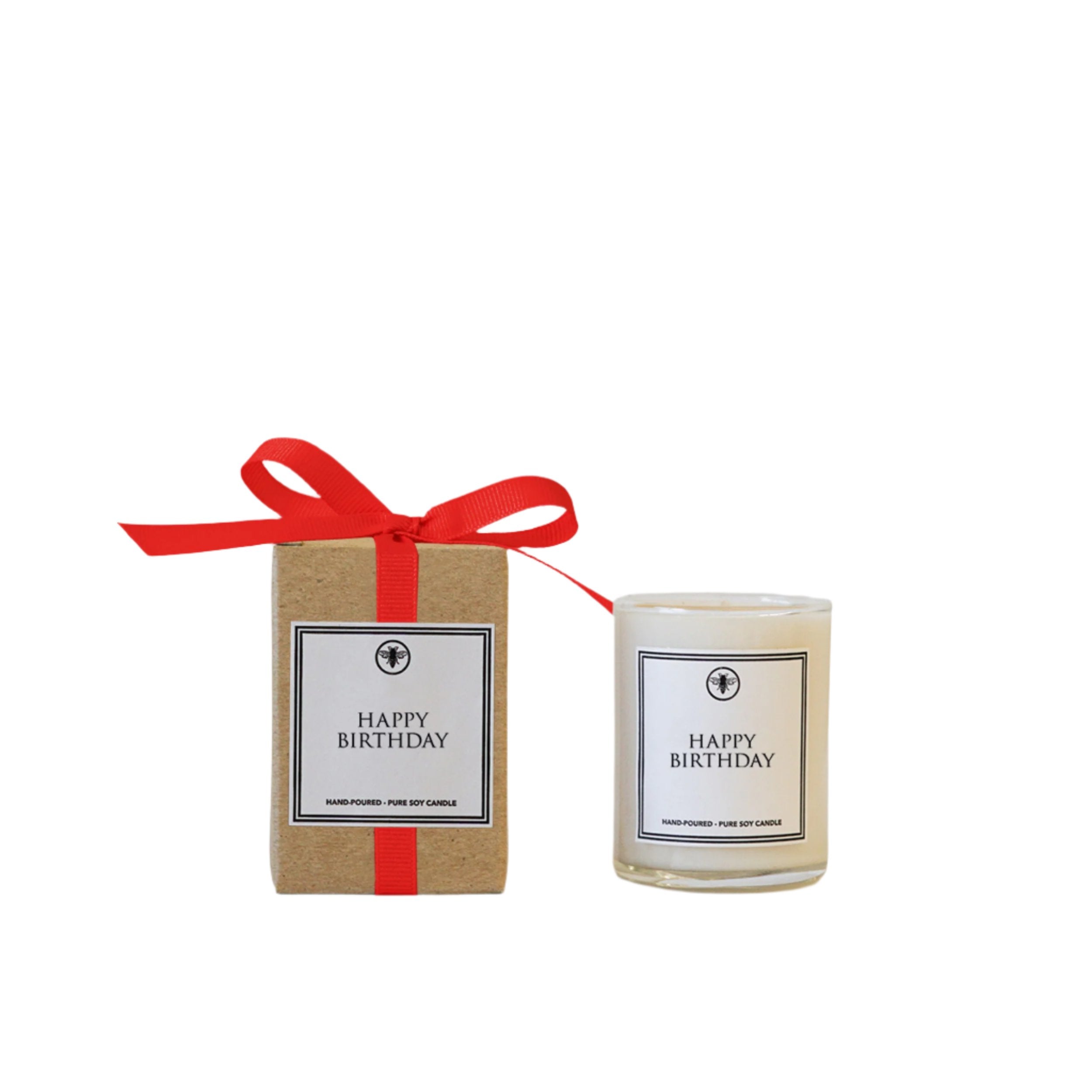 A 3oz candle with a white label that reads 'Happy Birthday', presented in a kraft paper box with a red ribbon. Available at Be Charmed