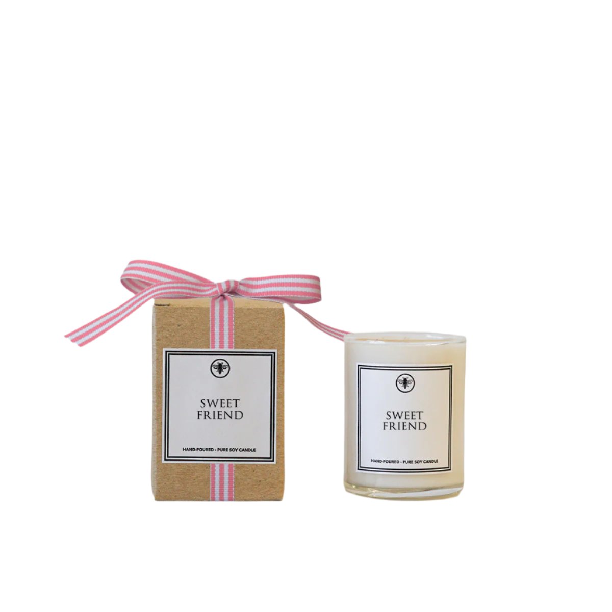 A beige candle with a label that reads 'Sweet Friend' and a pink ribbon on top of the candle, next to its cardboard packaging with a pink ribbon. Available at Be Charmed