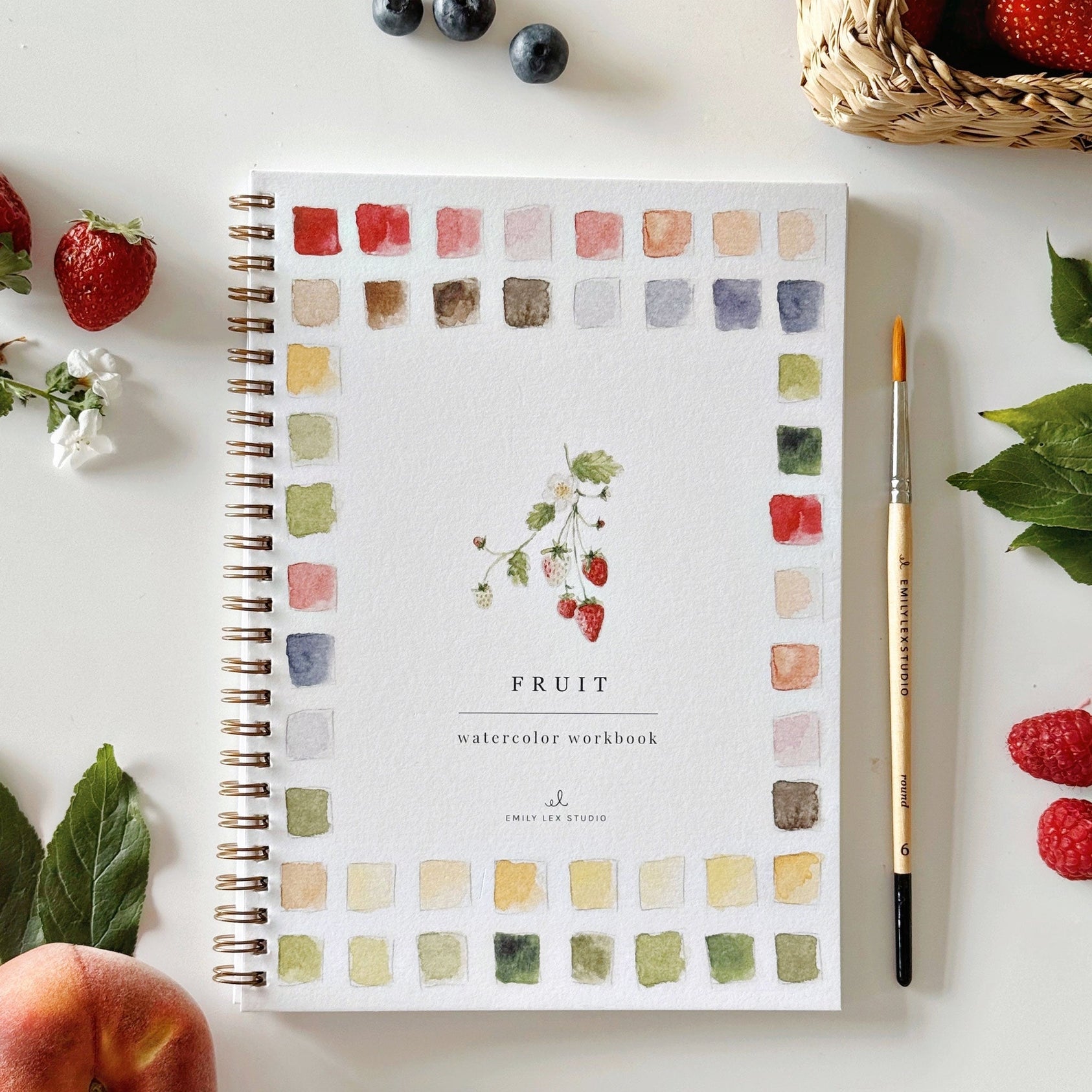 Watercolor workbook titled 'Fruit' with a pen and fruit on a white surface. Available at Be Charmed