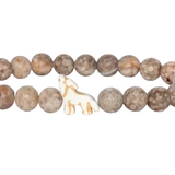 A beaded stretch Fahlo bracelet made of round, mottled brown and beige stone beads, featuring a small white carved wolf charm in the center, shown on a plain white background. Available at Be Charmed