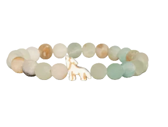 A beaded stretch Fahlo bracelet featuring round, polished beads in soft pastel shades of sage green, cream, and light brown, with a small white wolf charm at the center, shown on a plain white background. Available at Be Charmed
