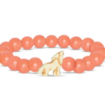 A beaded stretch Fahlo bracelet featuring smooth, round coral-pink beads and a small cream-colored wolf charm with gold-toned details, displayed on a clean white background. Available at Be Charmed