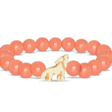 A beaded stretch Fahlo bracelet featuring smooth, round coral-pink beads and a small cream-colored wolf charm with gold-toned details, displayed on a clean white background. Available at Be Charmed