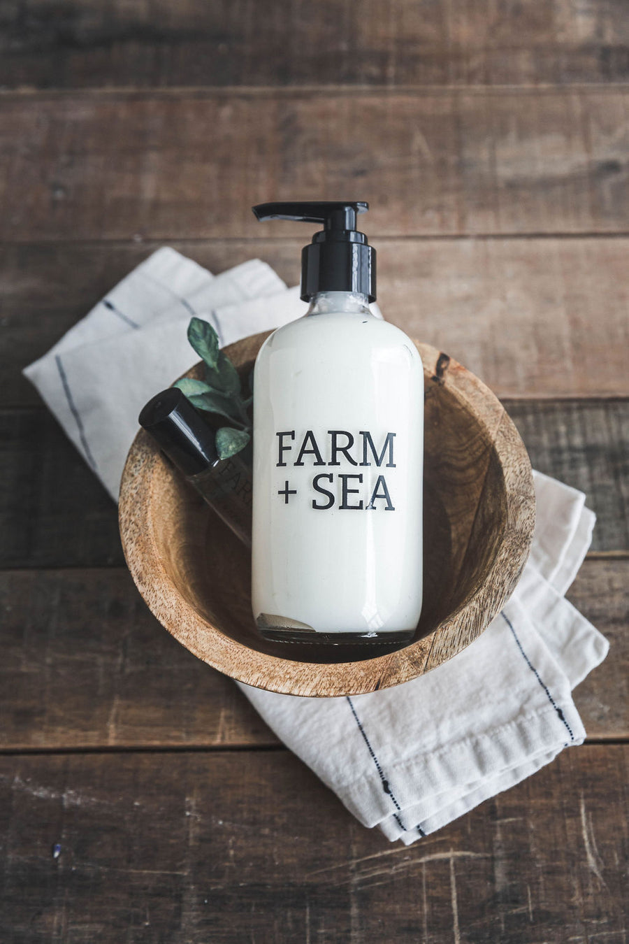 Farm + Sea Beach Girl glass pump body lotion with natural ingredients and coastal scent. Stylish and hydrating. Available at Be Charmed.