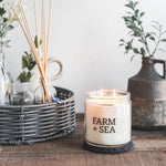 Farm + Sea Cozy Harbor 14 oz scented candle with warm, inviting aroma and natural ingredients. Clean-burning and long-lasting. Available at Be Charmed.