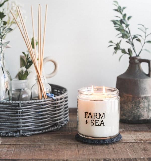 Farm + Sea Cozy Harbor 14 oz scented candle with warm, inviting aroma and natural ingredients. Clean-burning and long-lasting. Available at Be Charmed.