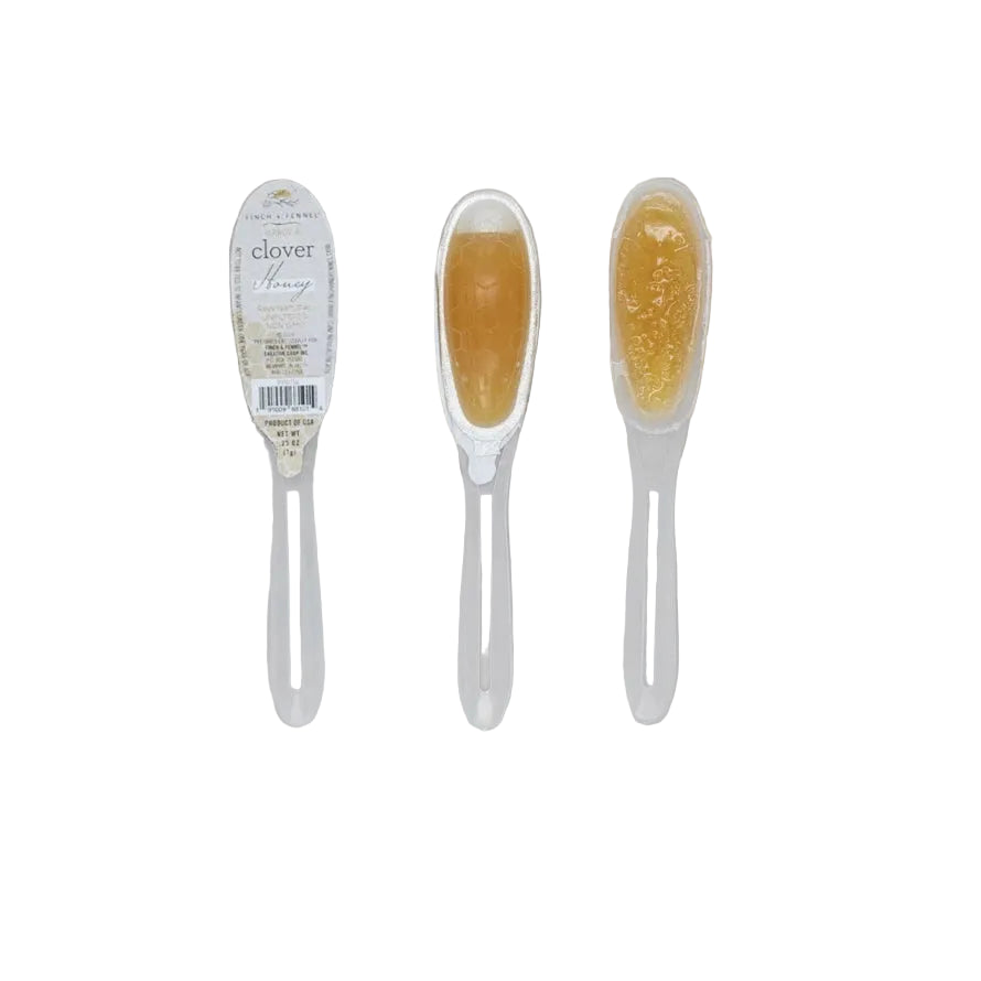 Two honey sticks with a label on a light gray background. Available at Be Charmed