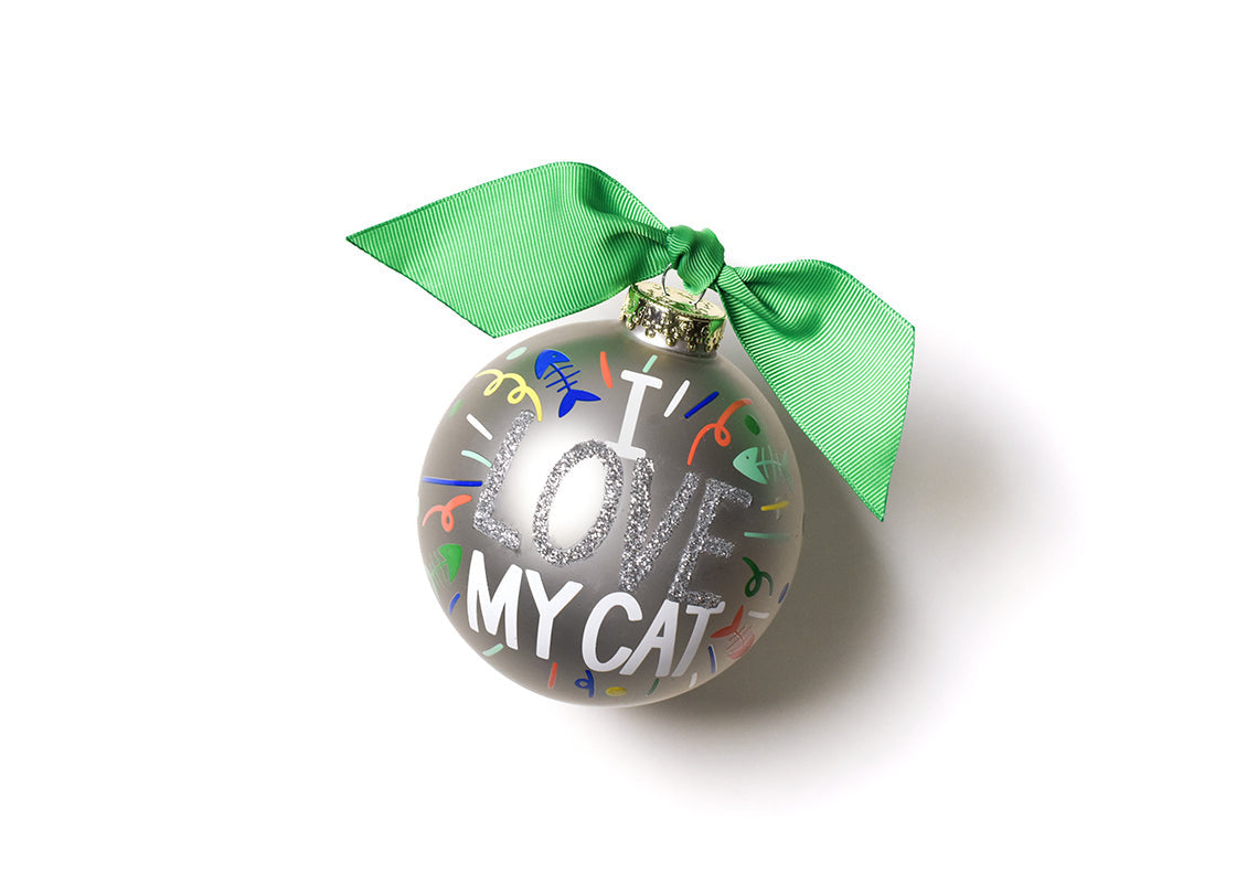Front view of Coton Colors “I Love My Cat” oversized silver popper glass ornament with hand-painted cat face, glitter accents, coordinating green ribbon & metal swirl stand — Available at Be Charmed