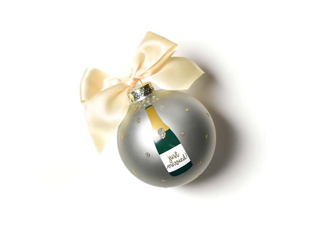 Front view of Coton Colors “Just Married” Champagne Pop glass ornament with hand-painted champagne bottle, gold glitter polka dots & cream ribbon; includes swirl stand & gift box – Available at Be Charmed