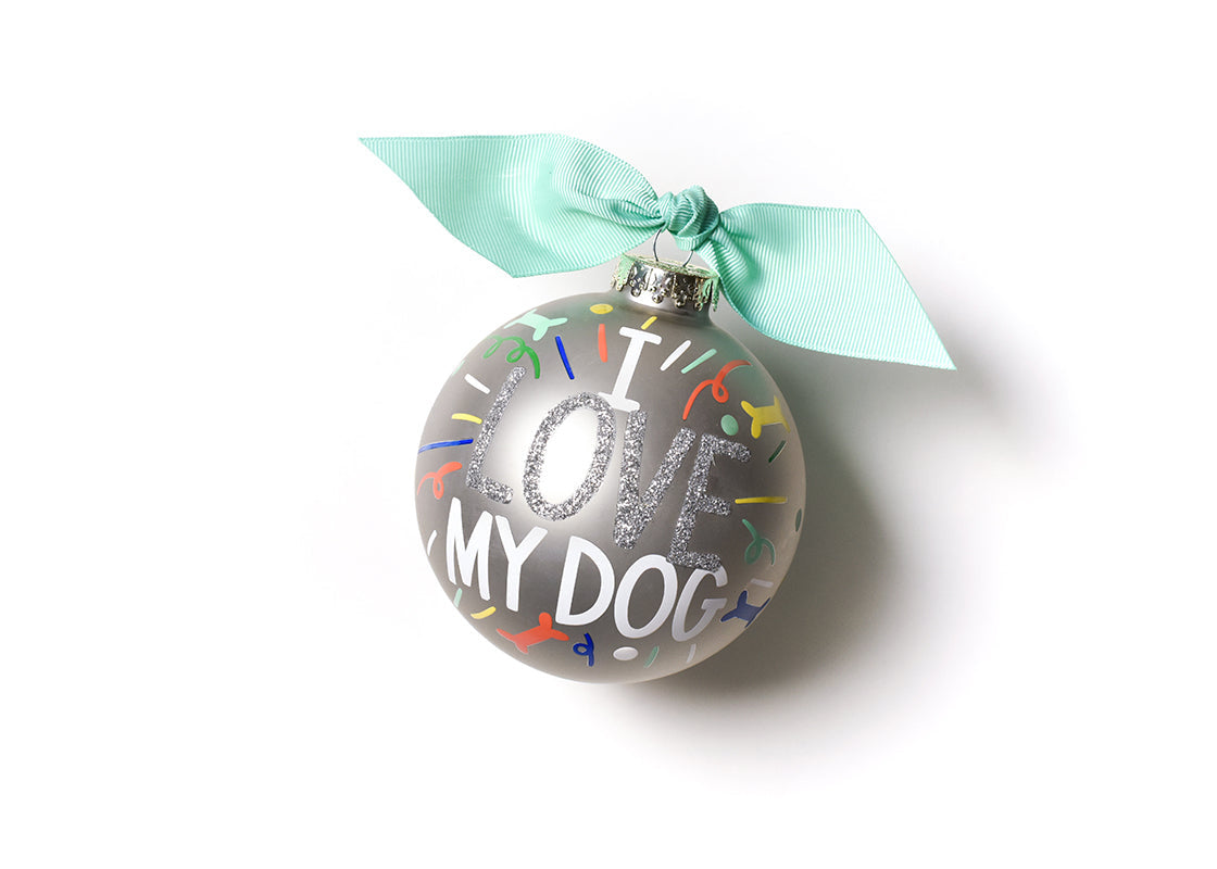 Front view of Coton Colors “I Love My Dog” oversized silver popper glass ornament with hand‑painted paw prints and silver glitter accent, includes swirled metal stand – Available at Be Charmed