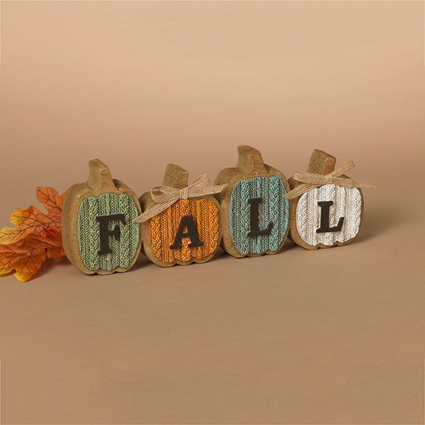 Decorative pumpkin sign with 'FALL' letters on a beige background. Available at Be Charmed.