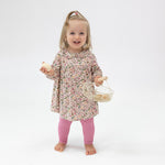 Girl wearing Angel Dear Acorn Floral Ruffle Dress and Leggings set for baby girls, featuring a delicate floral pattern and soft materials, available at Be Charmed.