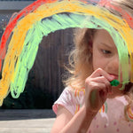 Girl drawing on window with Tiger Tribe Silk Crayons kids art set featuring smooth, vibrant twist-up crayons that work like pastels and watercolors. Creative art gift. Available at Be Charmed.