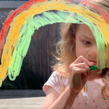 Girl drawing on window with Tiger Tribe Silk Crayons kids art set featuring smooth, vibrant twist-up crayons that work like pastels and watercolors. Creative art gift. Available at Be Charmed.
