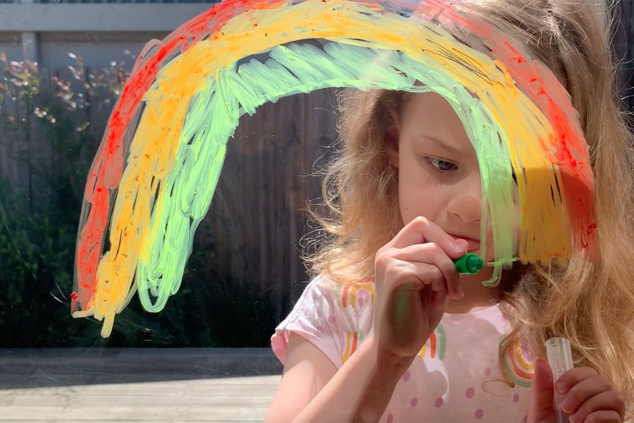 Girl drawing on window with Tiger Tribe Silk Crayons kids art set featuring smooth, vibrant twist-up crayons that work like pastels and watercolors. Creative art gift. Available at Be Charmed.