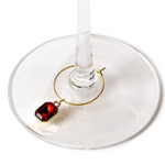 Wine glass with a red gemstone charm on a white background. Available at Be Charmed