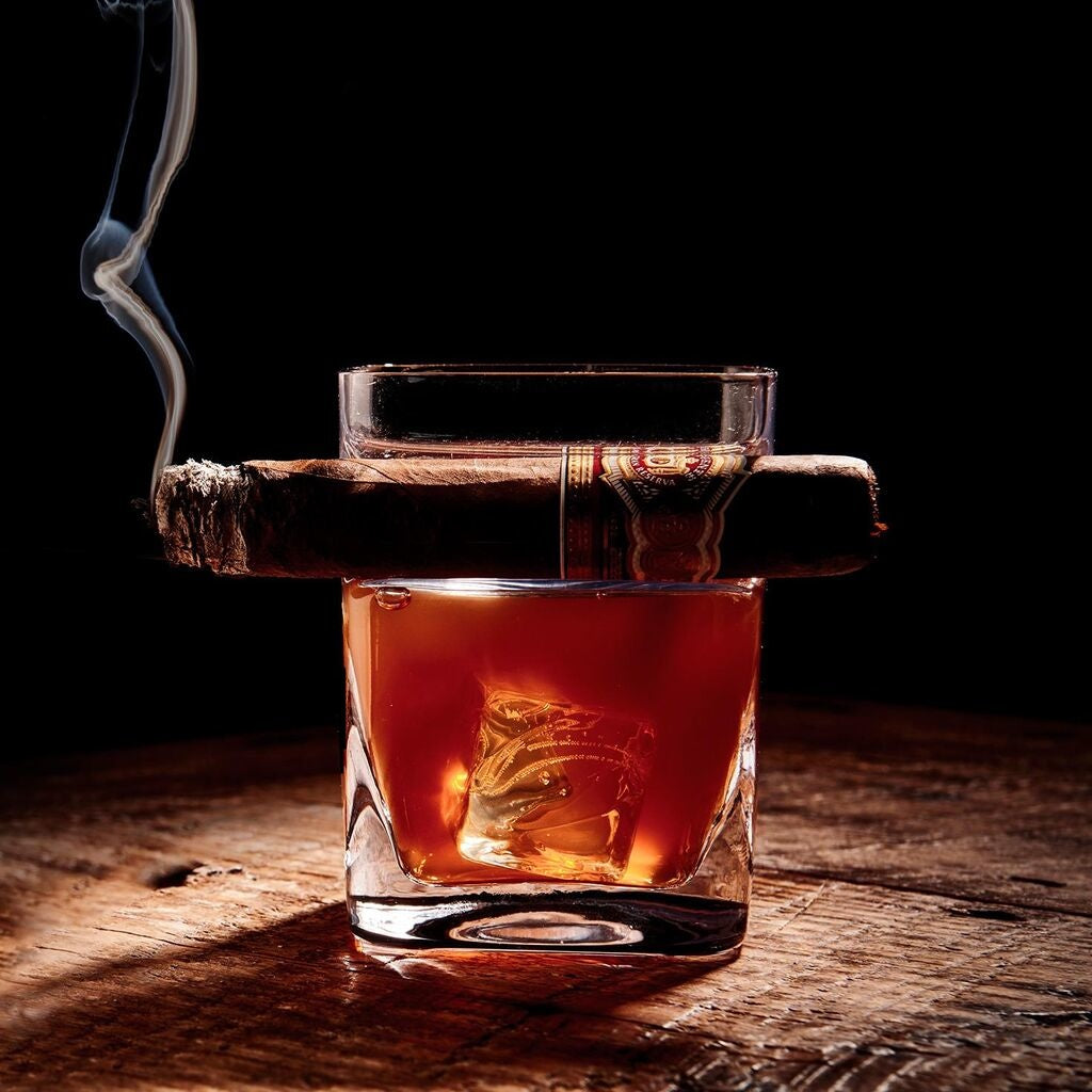 Glass with a cigar orkcicle Cigar Glass – unique double old-fashioned whiskey glass with built-in cigar holder, designed for effortless sipping and smoking in one hand. A refined gift for cigar and whiskey lovers, available at Be Charmed.