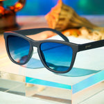 Goodr Drinks Seawater, Sees Future sunglasses sitting on book, featuring polarized reflective lenses and ocean-inspired frames—performance and style at Be Charmed.