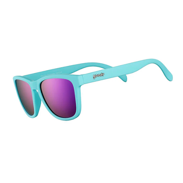 A pair of Goodr teal blue sunglasses with purple polarized lenses, featuring the brand name 'Goodr' on the side. Available at Be Charmed