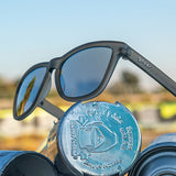 Goodr Going To Valhalla Witness Sunglasses Propped on bottles featuring polarized black lenses and a no-slip frame, inspired by Viking grit and perfect for outdoor adventures, Available at Be Charmed