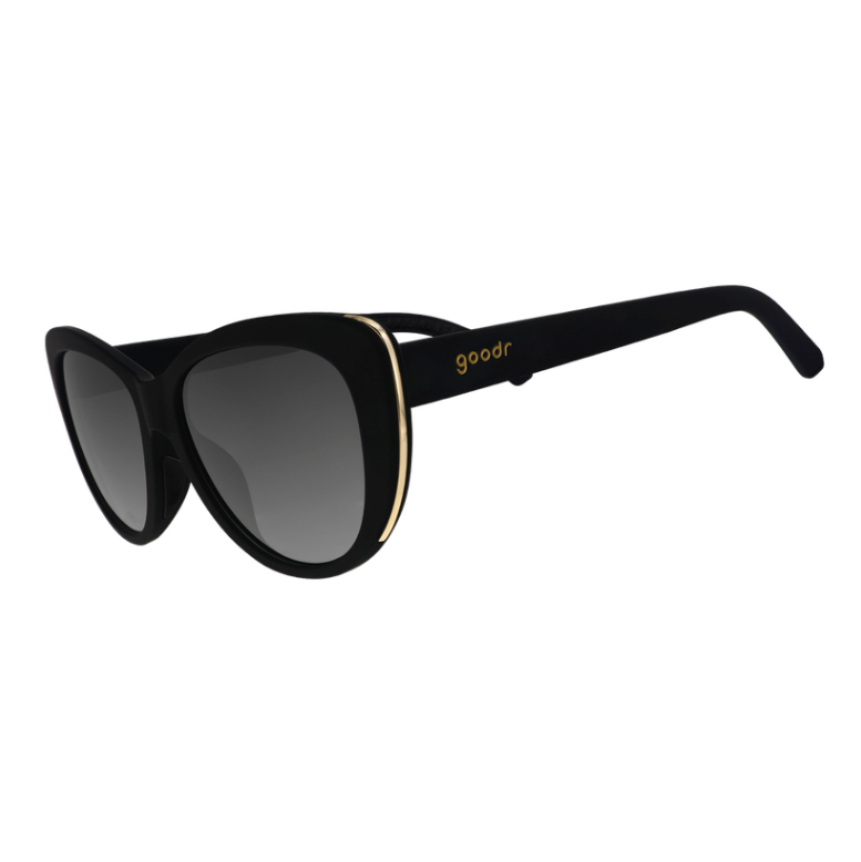 Black cat-eye Goodr sunglasses with black non-reflective lenses and light gold accents on the frames. Available at Be Charmed