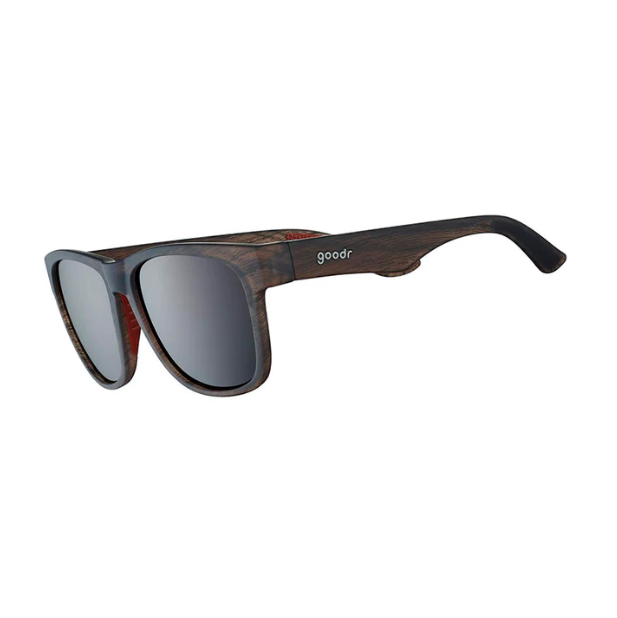A pair of wood grain Goodr sunglasses with black and red accents on the arms, with a clear lens. Available at Be Charmed