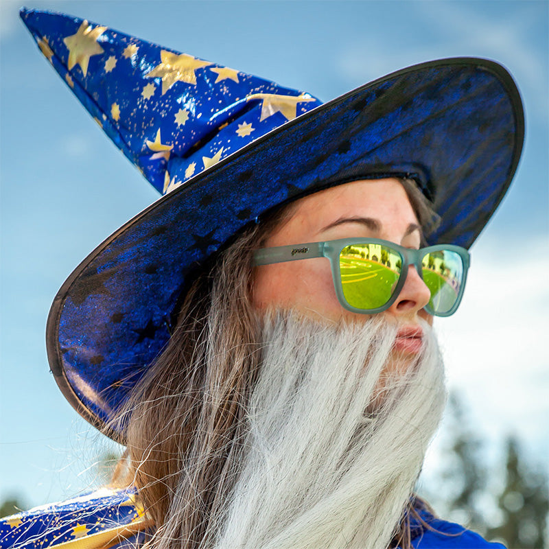 Wizard Wearing Goodr Sunbathing with Wizards Sunglasses featuring vibrant blue frames and green polarized lenses, combining mystical style with sport-ready performance, available at Be Charmed