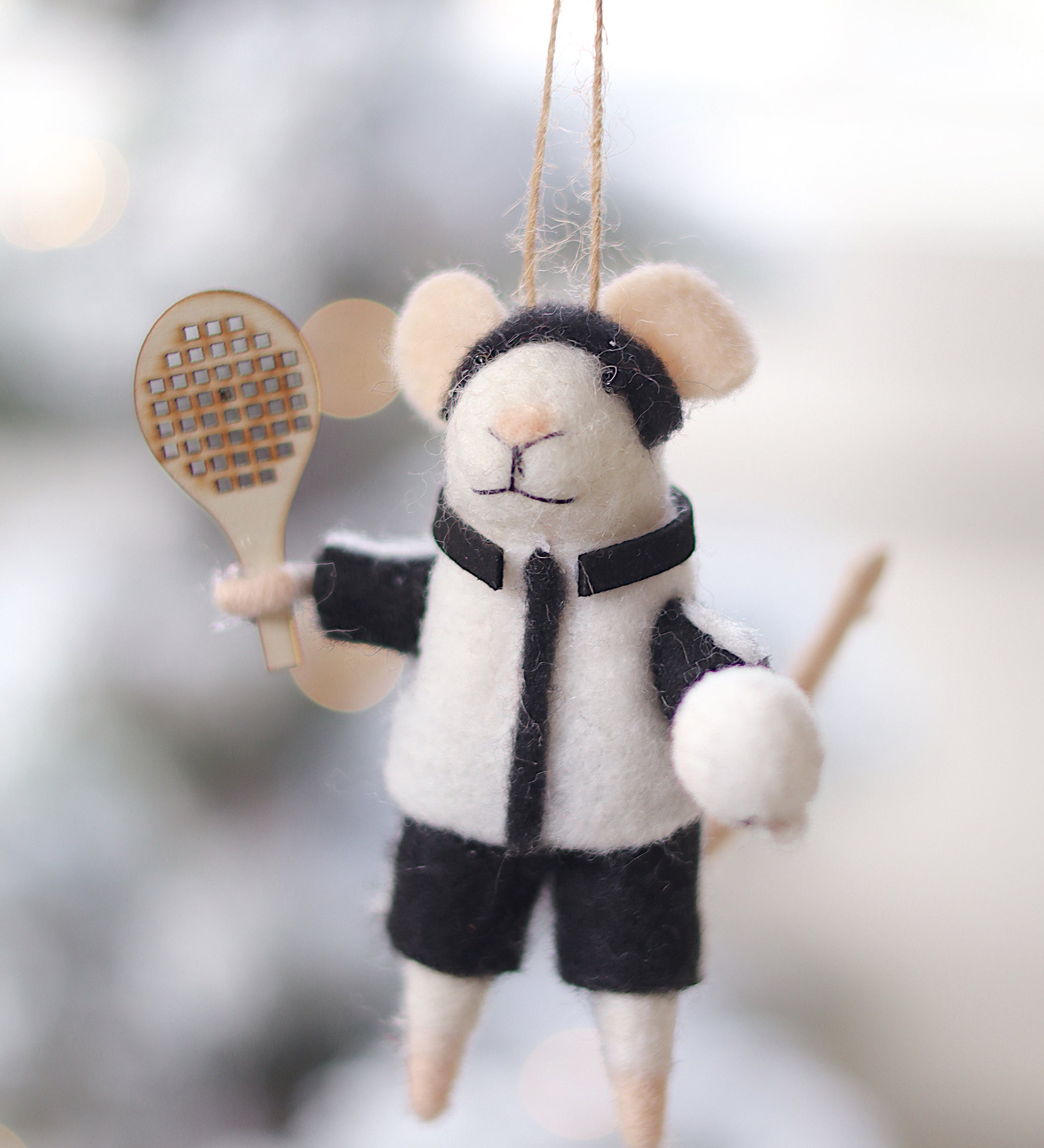 Felt mouse ornament with a tennis racket and ball on a blurred snowy background. Available at Be Charmed