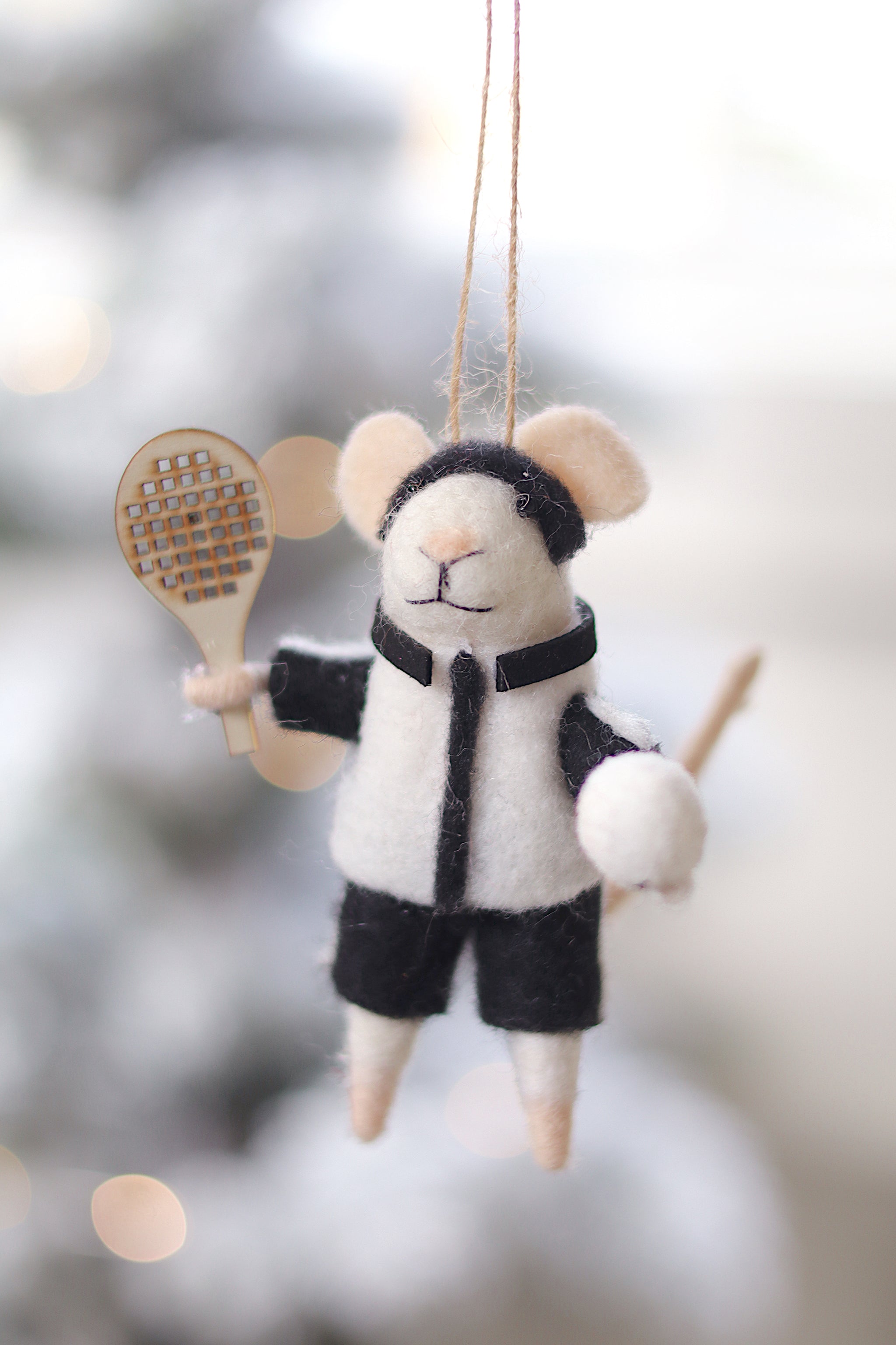 Felt mouse ornament with a tennis racket and ball on a blurred snowy background. Available at Be Charmed