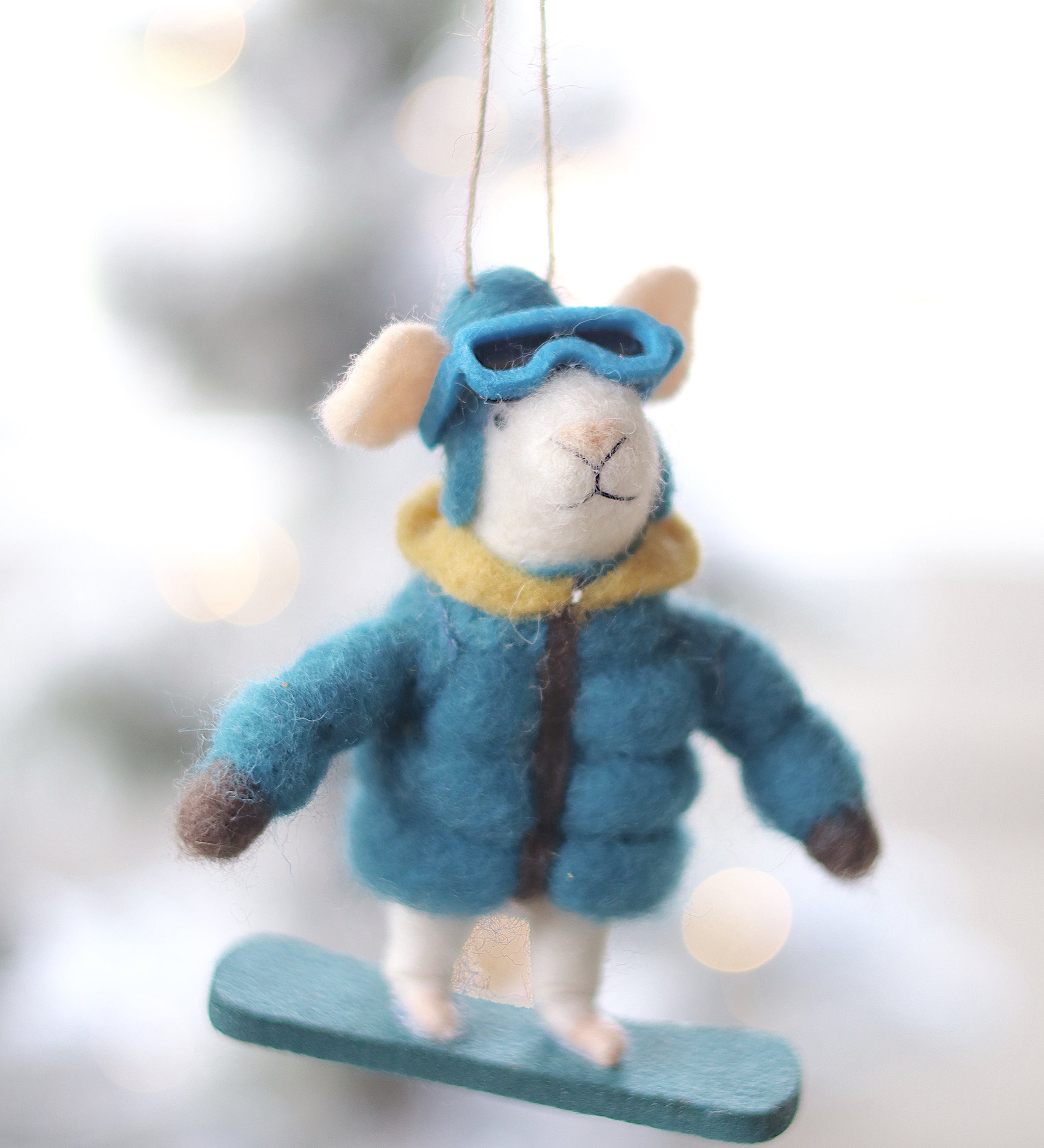 Decorative ornament of a mouse in winter clothing hanging against a blurred snowy background. Available at Be Charmed