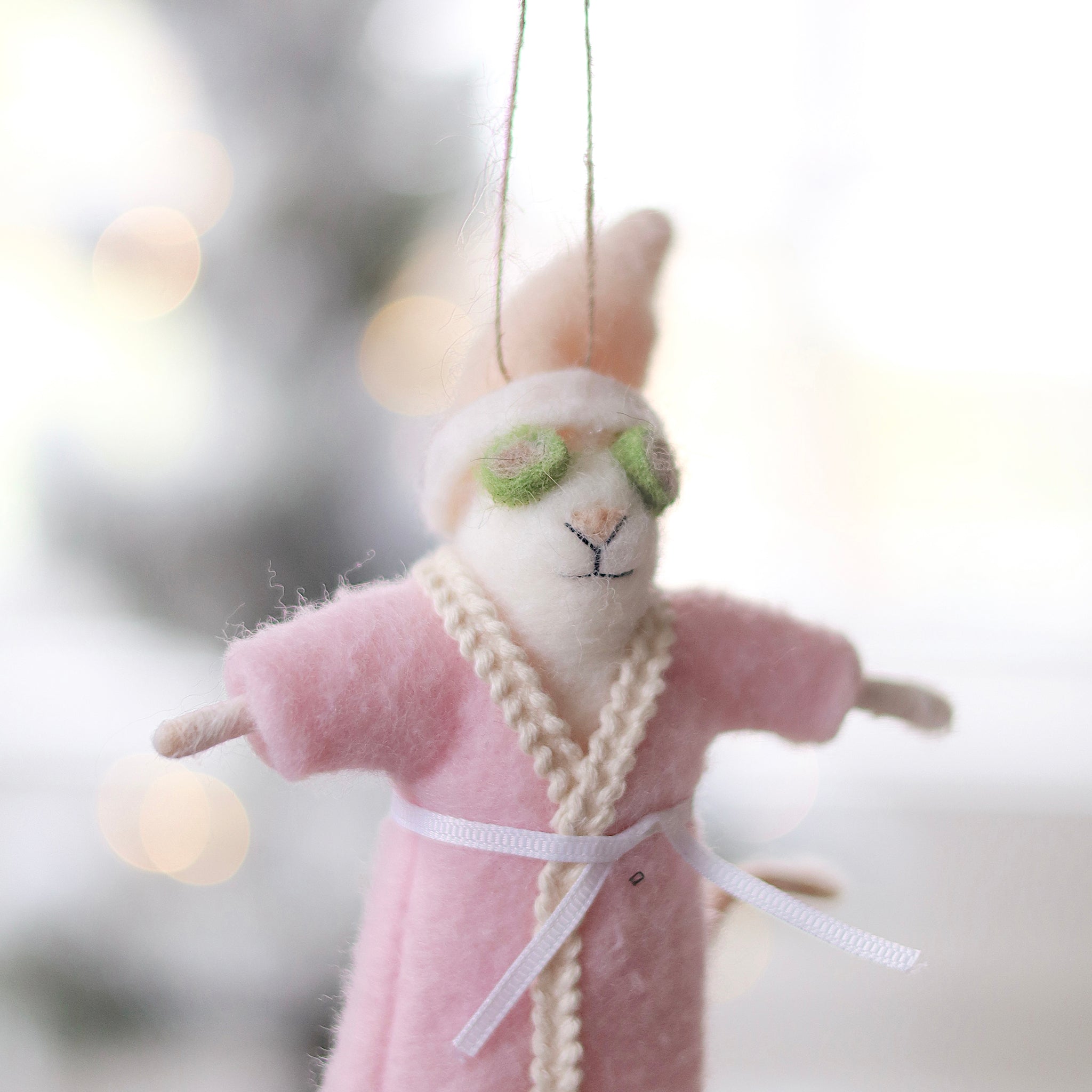 Person holding a plush mouse ornament in a pink robe with green glasses, hanging against a blurred background. Available at Be Charmed