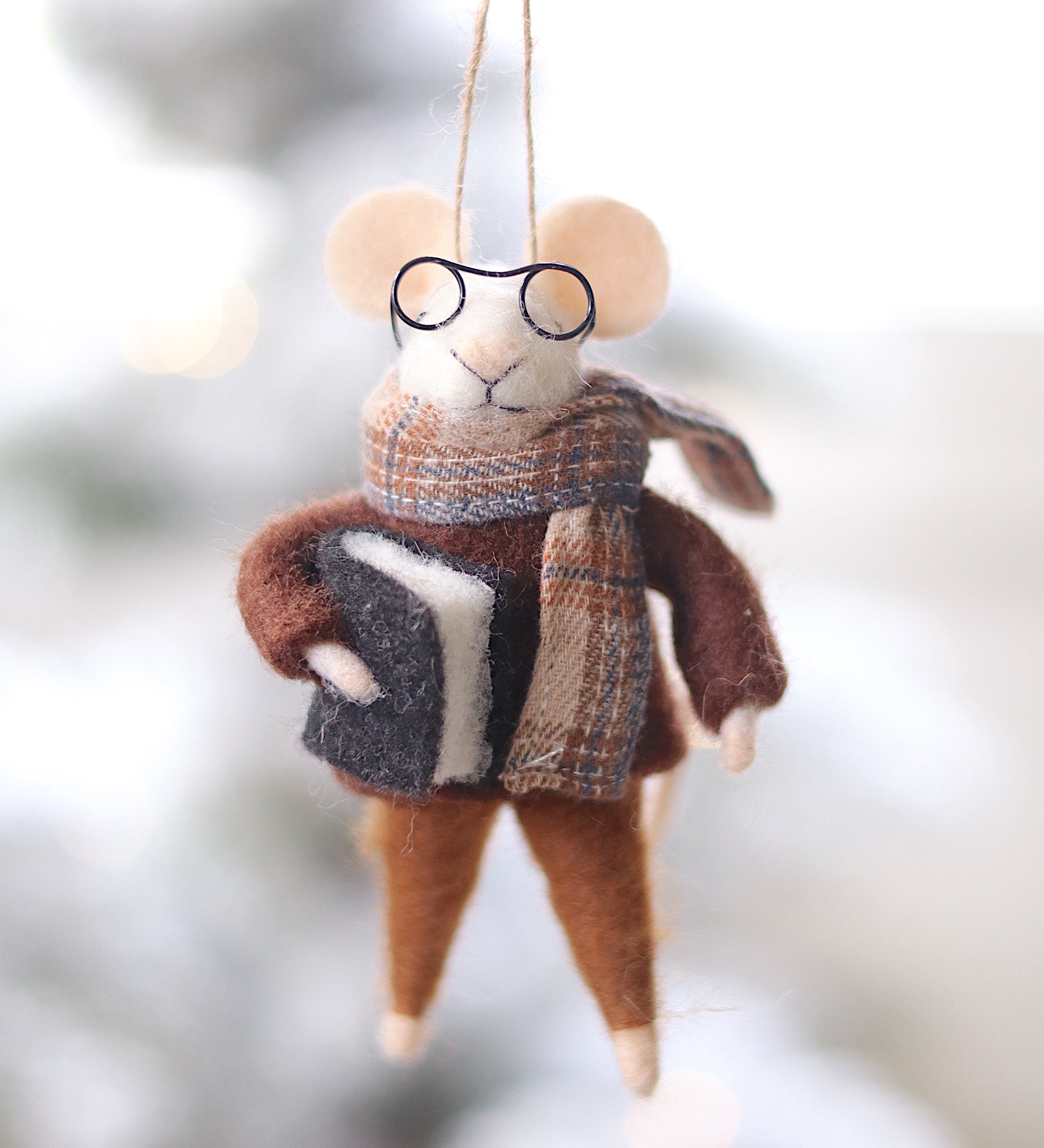 Felt mouse ornament with glasses and a scarf hanging against a blurred natural background. Available at Be Charmed