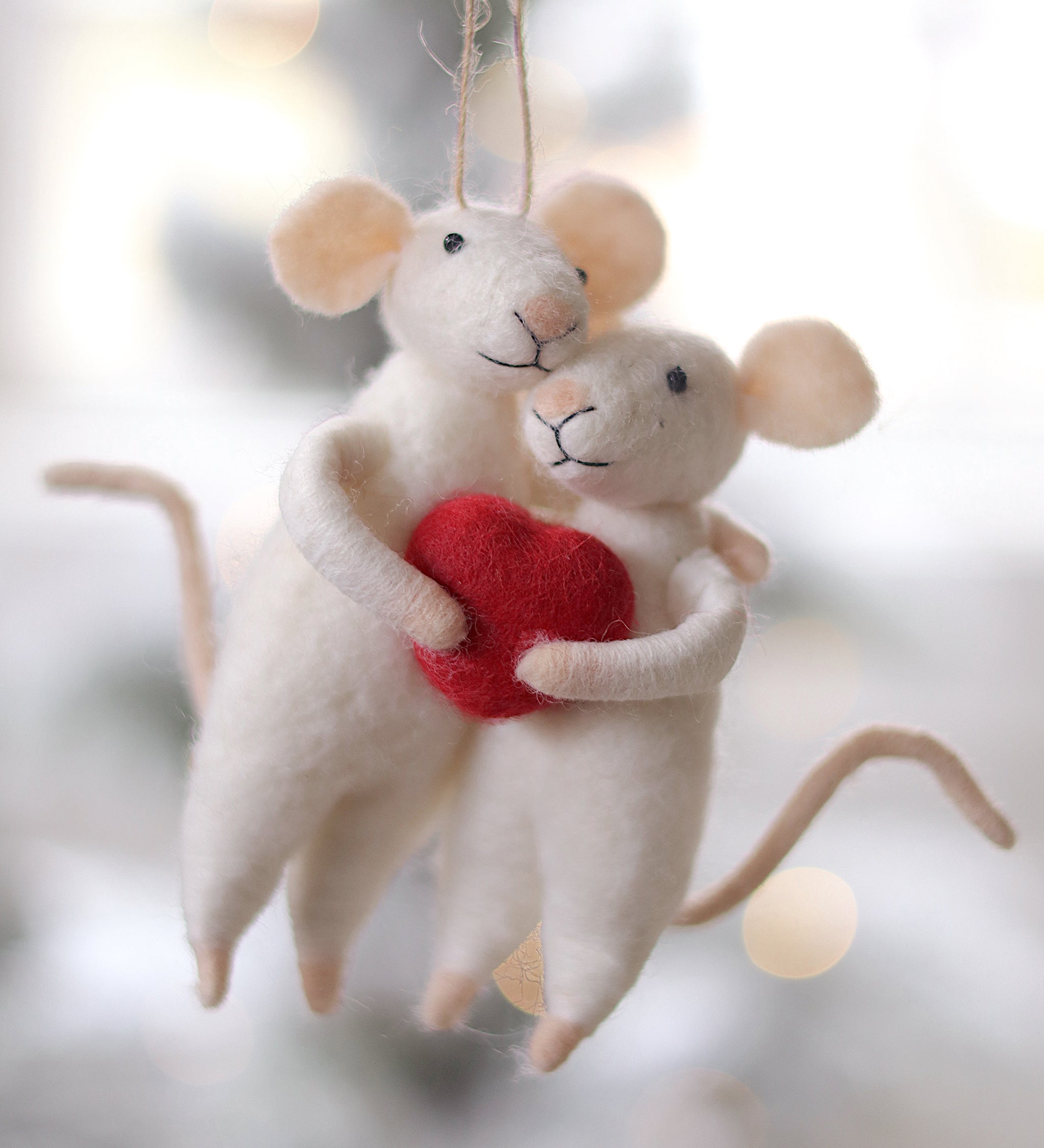 Two mouse ornaments holding a red heart against a blurred background. Available at Be Charmed