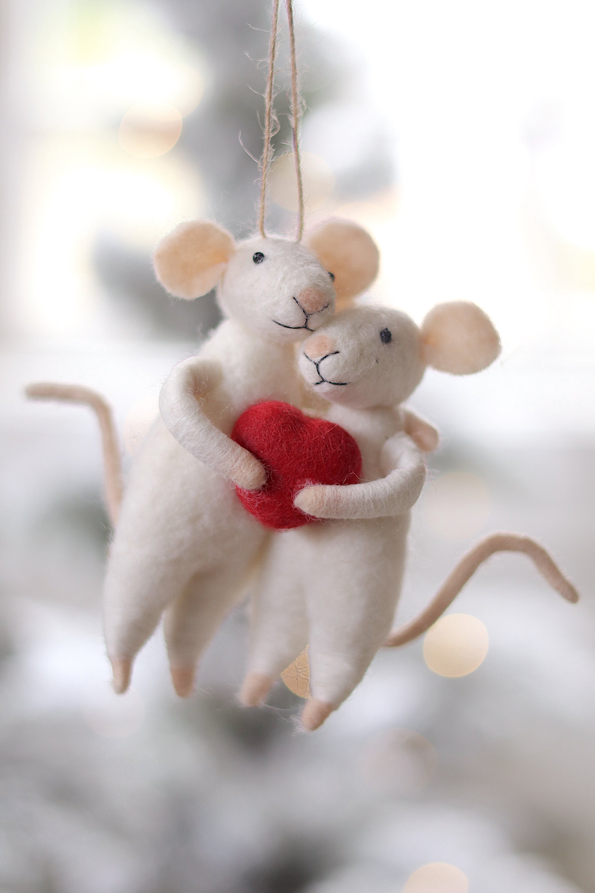 Two mouse ornaments holding a red heart against a blurred background. Available at Be Charmed