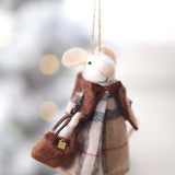 Felted mouse ornament with plaid dress and scarf, held against a blurred snowy background. Available at Be Charmed