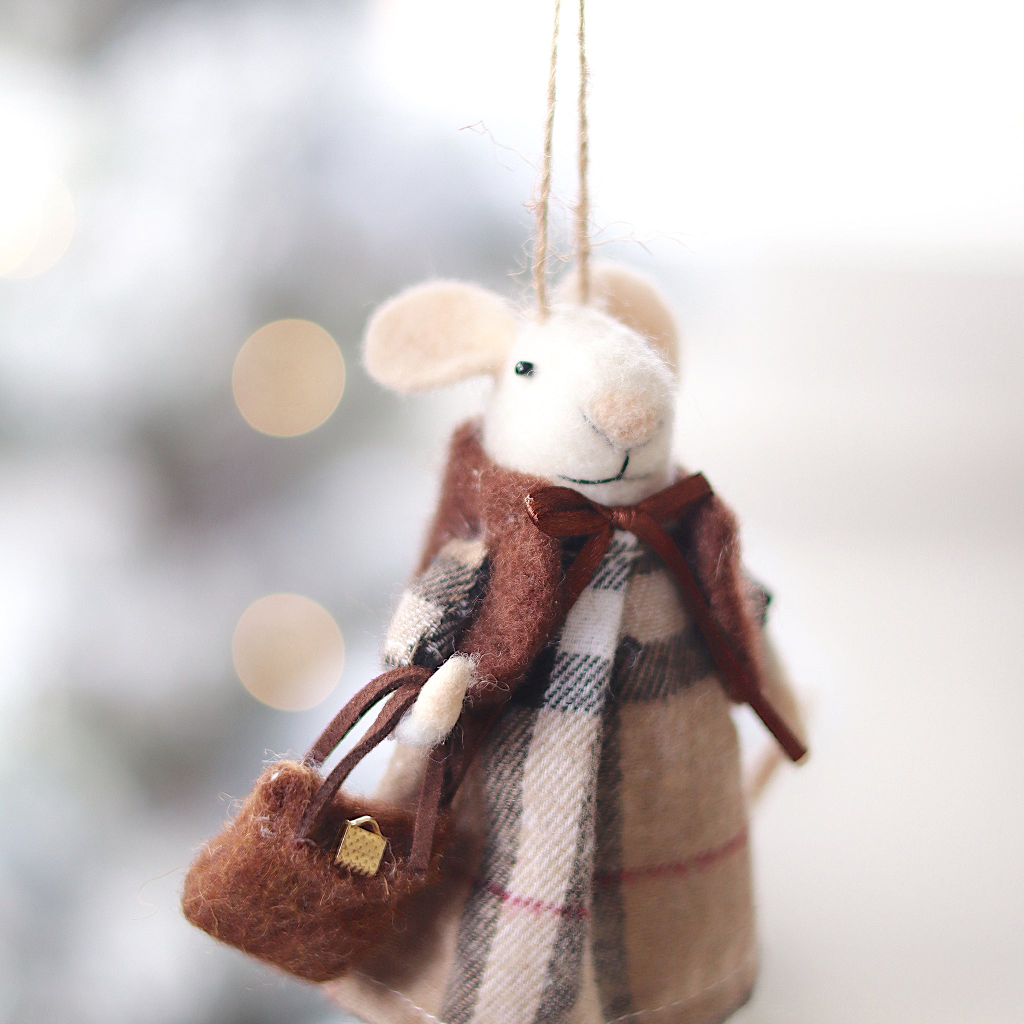 Felted mouse ornament with plaid dress and scarf, held against a blurred snowy background. Available at Be Charmed