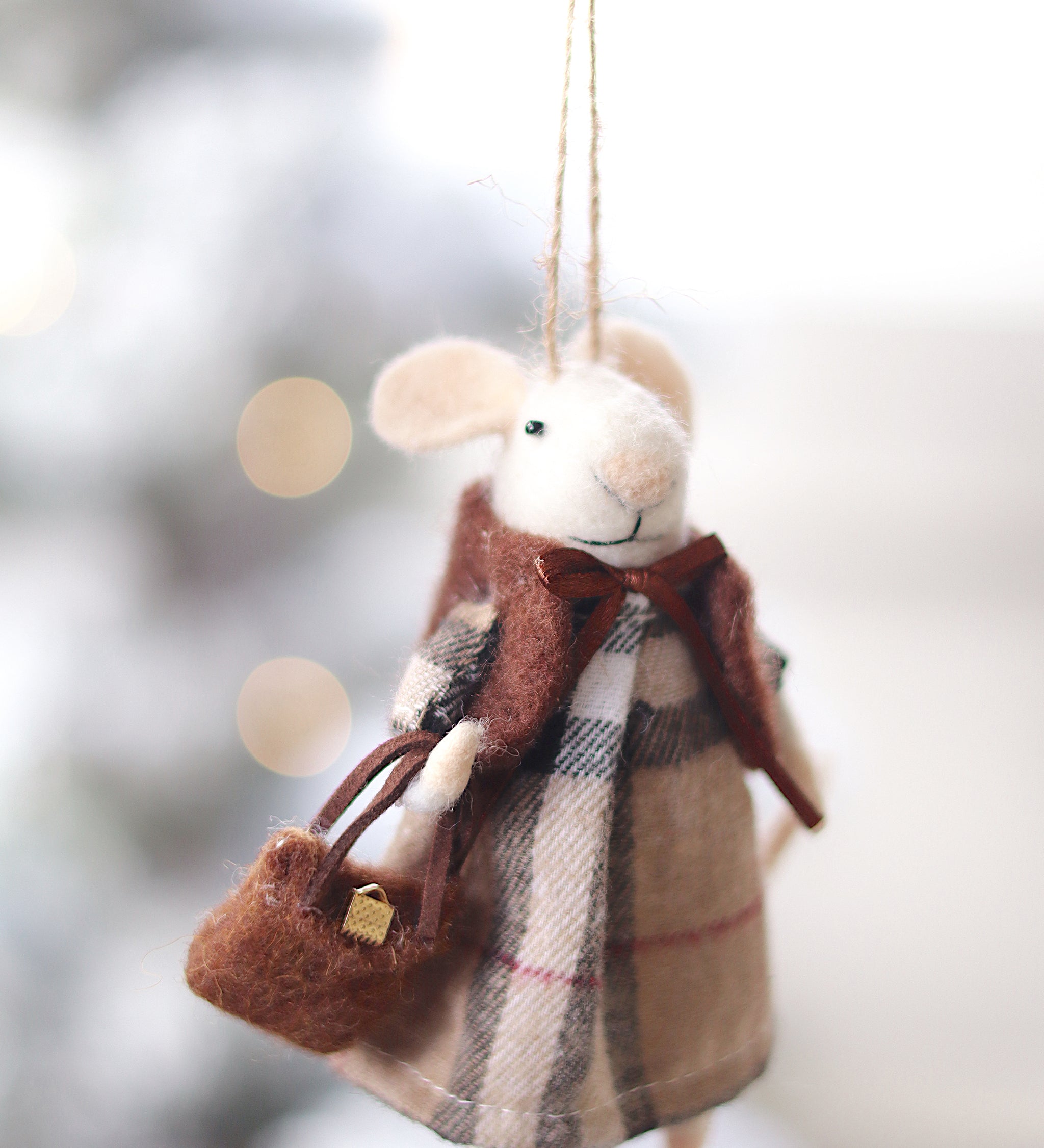 Felted mouse ornament with plaid dress and scarf, held against a blurred snowy background. Available at Be Charmed