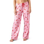 Pink pajama pants with red cherry pattern worn by a person on a white background. Available at Be Charmed