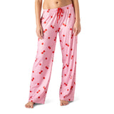 Pink pajama pants with red cherry pattern worn by a person on a white background. Available at Be Charmed