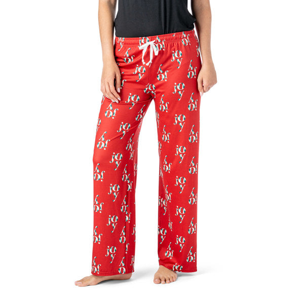 Red pajama pants with 'joy' and Santa Claus print on a white background. Available at Be Charmed