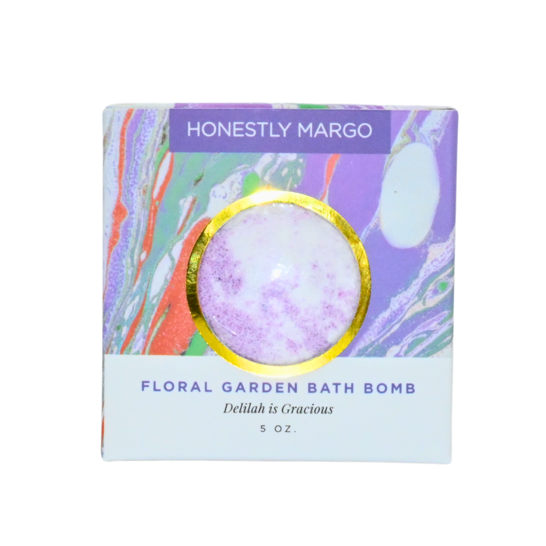 Floral garden bath bomb packaging with 'Honestly Margo' branding on a white background. Available at Be Charmed
