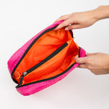 Pink Scout pouch with orange interior being held open by a hand on a white background. Available at Be Charmed