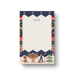 A vertical Rifle Paper notepad with a winter ski-themed border design. The top section is cream-colored with the word 'NOTES' printed in gray, while the bottom and side borders feature a colorful pattern of skiers, a cabin, a tree, and snow in navy, red, green, and beige tones. Available at Be Charmed
